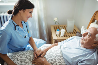 A nurse discussing Advance Health Care Directives with an elderly man lying in bed - The Law Office of Rebecca Sommer