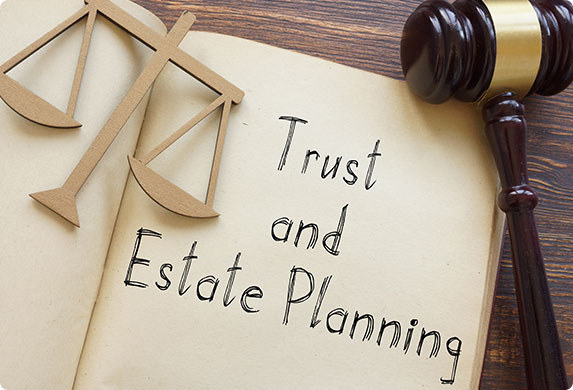 "Trust and Estate Planning" book with a gavel and wooden justice scale on top.